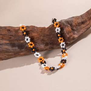 Macro detail of handmade beaded floral necklace on rustic dark wood background