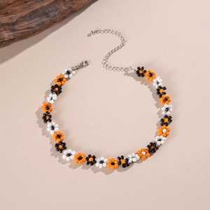 Detail of handcrafted beaded flower necklace with silver lobster clasp on a beige background