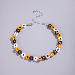 Detail of handmade beaded daisy necklace with orange, black and white pearls and silver clasp