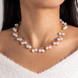 Elegant gold wavy chain necklace with white imitation pearls on a white sweater model