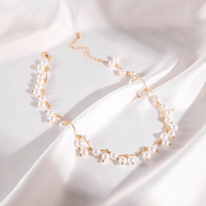 Detail of floral gold pearl choker necklace on elegant white satin fabric background