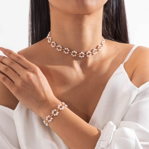 Elegant pearl necklace and bracelet set featuring gold floral accents on a female model