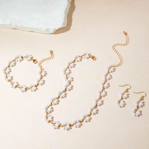 Detail of faux pearl jewelry set with necklace and earrings on beige textured stone background
