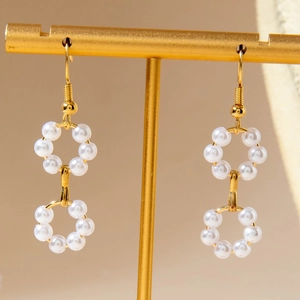 Detail of double pearl hoop earrings hanging on golden jewelry display stand