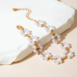 Detail of floral imitation pearl necklace with gold-plated clasp on a stone display