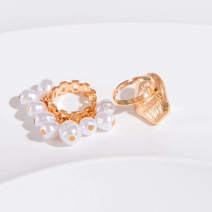 Detailed view of gold-finish ring set featuring baroque pearls and geometric shapes