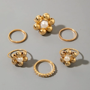 Detailed flat lay of 6-piece gold alloy ring set with pearls and rhinestones