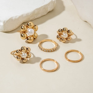Detail of 5-piece gold ring set featuring baroque pearls and rhinestones on stone base