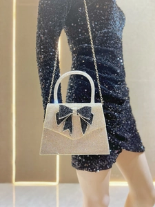 Detail of champagne gold evening bag with rhinestone bow and gold chain strap