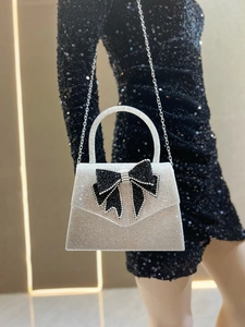 Detail of silver rhinestone evening bag with black crystal bow on black sequin dress