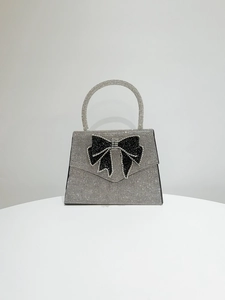 Macro shot of silver rhinestone evening bag featuring a large black crystal bow decoration