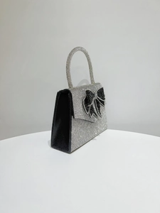 Detail of silver rhinestone evening bag with black crystal bow and top handle