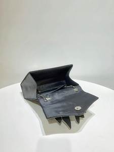 Detail of black clutch interior showing magnetic closure and silver chain strap