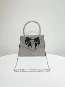 Macro shot of silver rhinestone handbag featuring a black crystal bow accent