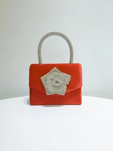 Detail of red velvet evening clutch with a sparkling silver rhinestone rose ornament