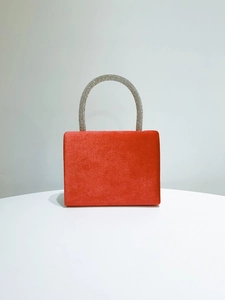 Detail of red satin evening bag featuring a silver rhinestone encrusted handle