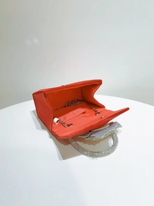 Detail of red satin evening bag showing diamond-set ring handle and inner chain strap