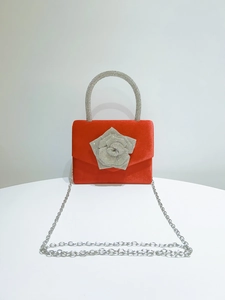 Close-up of red satin evening clutch with silver rhinestone flower and crystal handle
