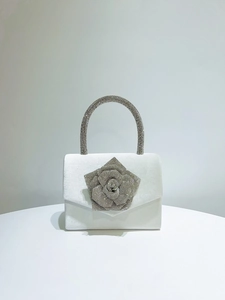 Detailed view of white satin evening bag with a large 3D rhinestone rose and crystal handle
