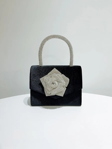 Detail of velvet evening bag featuring crystal rhinestone rose and sparkling handle