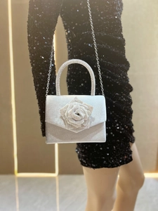 Silver evening bag with crystal rose detail and chain strap worn by a model