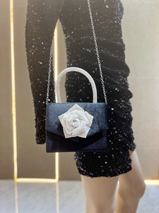 Detail of luxury navy evening bag with rhinestone rose decor and metallic strap