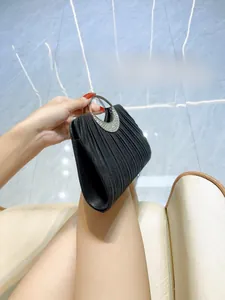 Detail of black pleated evening clutch with rhinestone-studded round metal handle