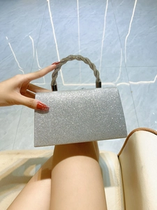 Detail of silver glitter evening clutch featuring a spiral rhinestone top handle design