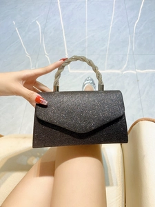 Close-up of black glitter evening clutch bag with sparkling diamond-encrusted round handle