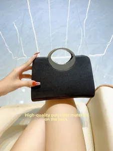 Detail showing high-quality polyester back and silver circular metal handle on black clutch