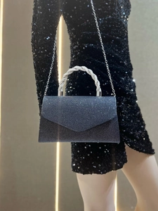 Detail of black sequined clutch featuring a sparkling rhinestone handle and silver chain