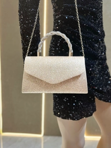 Detailed view of shimmering gold glitter clutch with rhinestone handle and chain strap