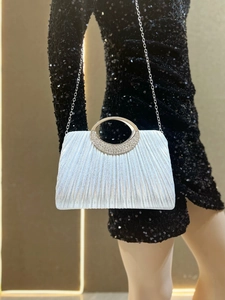 Detail of silver pleated evening clutch bag with rhinestone handle and metal chain strap