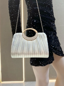 Close-up of pleated silver evening clutch with sparkling rhinestone circular handle