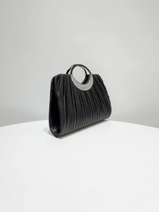 Detailed side view of black pleated fabric evening bag with rhinestone silver handle