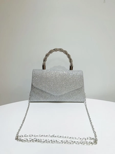 Detail of silver sequined clutch bag featuring a twisted rhinestone handle and chain strap