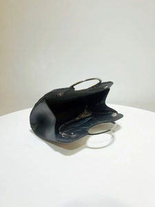 Detail of black satin evening bag showing magnetic closure and interior chain strap