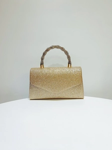 Close-up of golden evening clutch with sparkling sequins and rhinestone twisted handle