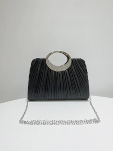 Detail of black pleated evening bag with silver circular handle and rhinestone inlay