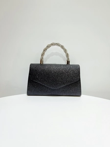 Detail of black glitter evening bag with sparkling rhinestones and twisted handle