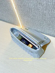 Detailed view of spacious silver evening bag interior holding phone and makeup accessories