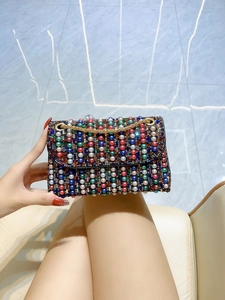 Detail of colorful pearls and rhinestones on luxury evening clutch with gold chain strap