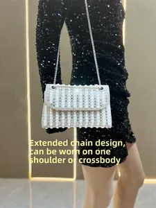 Detail of white pearl evening bag with rhinestone accents and long silver chain strap