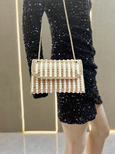 Macro shot of elegant evening clutch with white pearls and gold metal chain strap