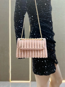 Detail of evening clutch bag with pearl and rhinestone inlay on a gold chain strap