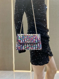 Detailed view of colorful beadwork and gold chain strap on an evening clutch bag
