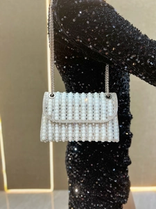Macro detail of luxury evening clutch with radiant pearls, rhinestones, and silver chain