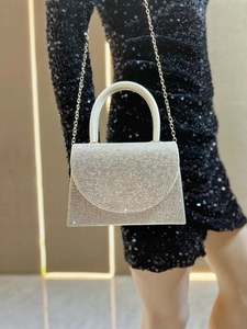 Silver rhinestone evening clutch bag with top handle and gold chain on sequin dress