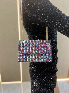 Detail of luxury evening bag with colorful pearls and rhinestones on black sequin dress