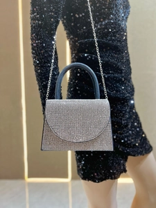 Detail of silver rhinestone evening clutch with black leather handle and metal chain strap